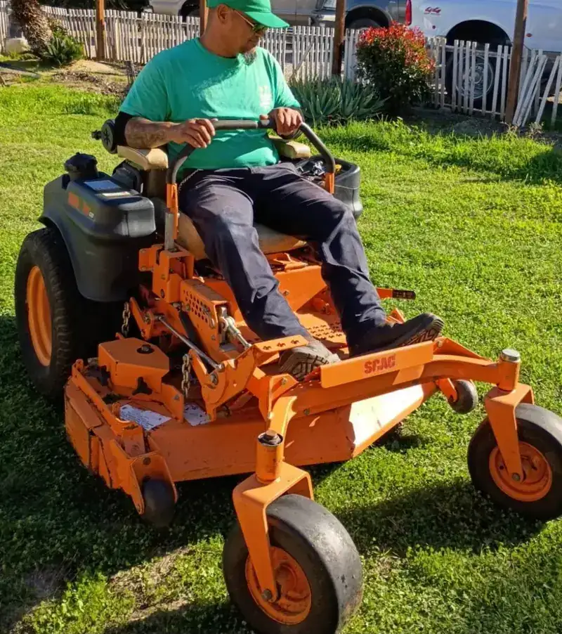 Miracle Green crew member mowing a lawn on a commercial zero-turn mower